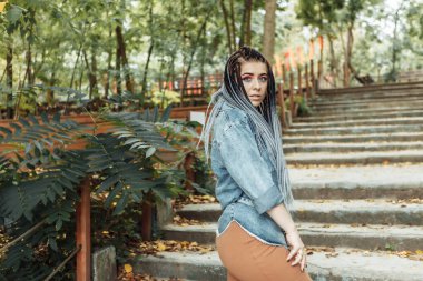 Parkta yürüyen Afrikalı örgülü olağanüstü kadın öğrenci milenyumu.