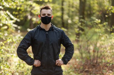 Ormanda koruyucu yüz maskesi takmış aktif bir adamın portresi