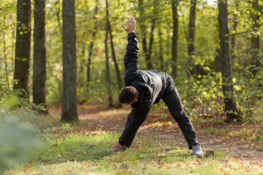Aktif sporcu ısınma egzersizleri ya da sonbahar ormanlarında esneme hareketleri yapar. Sağlıklı bir yaşam tarzı. Açık hava egzersizi.