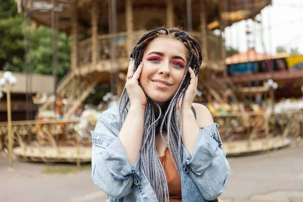 Extraordinary woman with African braids and flamboyant makeup spends time in an amusement park