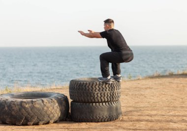 Aktif fitness elemanı açık hava antrenman sahasında tekerlekli sandalyeye atlıyor. Çapraz eğitim