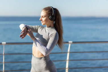 Parlak güneşli bir günde akıllı bir saat arayan bir kadın.