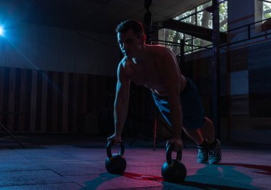 Kas yığını adam kırmızı-mavi renkte kettlebell ile yukarı itin.