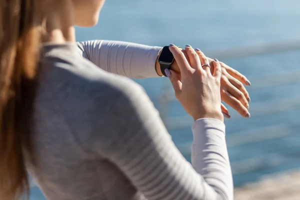 Woman looking in smart watch on bright sunny day