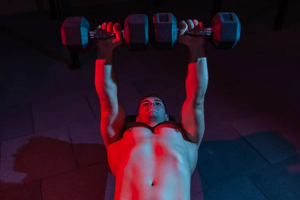 Muskelkräftiger Mann Trainiert Bankdrücken Mit Kurzhanteln Übung Rot Blauem Neonlicht — Stockfoto