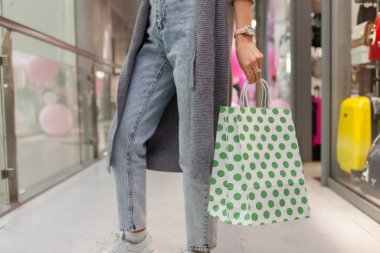 Alışveriş merkezindeki bir kadının elinde alışveriş paketi.