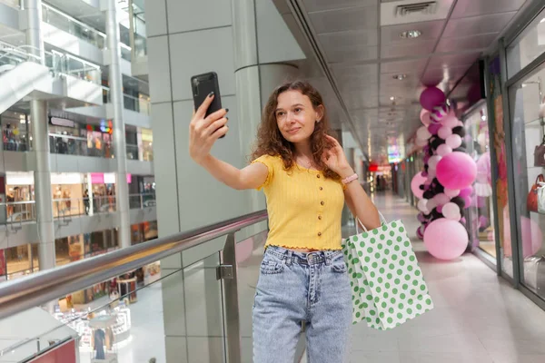 Słodka Kobieta Kręconymi Włosami Robi Selfie Torbami Zakupy Centrum Handlowym — Zdjęcie stockowe