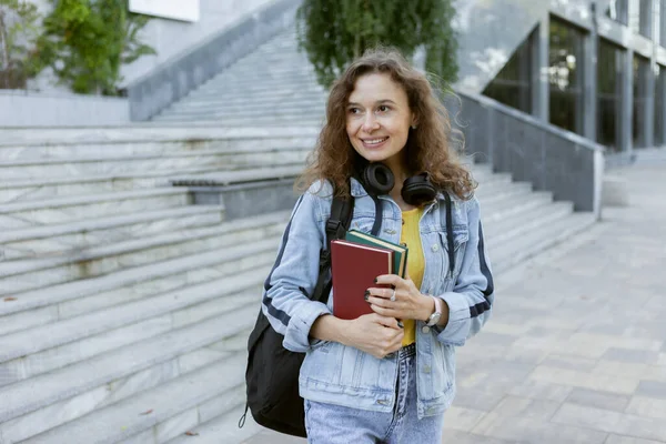 Atraktivní Studentka Středního Věku Kudrnatými Vlasy Stylovém Denimovém Oblečení Knihami — Stock fotografie