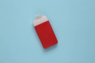 Mavi arka planda kırmızı şampuan şişesi. Üst görünüm