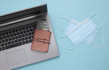 Laptop ve tıbbi maskeler, mavi arka planda cüzdan. Üst görünüm
