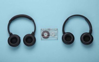 Mavi arka planda iki çift siyah stereo kulaklık ve ses kaseti.