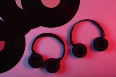 İki çift siyah stereo kulaklık ve kırmızı mavi ışıklı vinil plaklar.