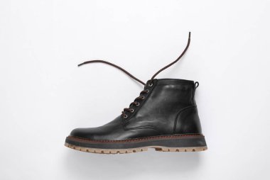 Beyaz arka planda bağcıkları çözülmüş şık erkek deri çizmeleri.