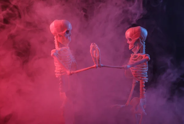 Skeletons in dense smoke with red purple neon light. Scary, Halloween theme