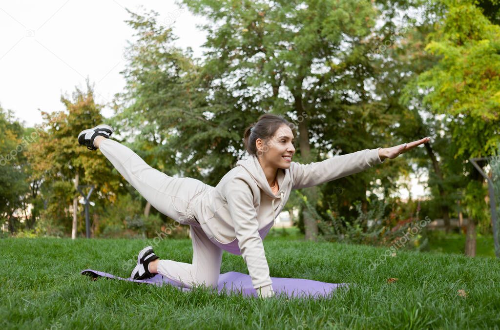 Fit woman doing yoga or pilates exercises on the mat outdoor. Chakravakasana pose
