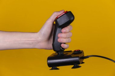 Eller sarı arka planda retro joystick 'i tutuyor. Eski oyun. 80 'lerin retro dalgası