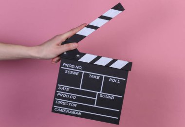 Pembe arka planda el ele tutuşan el çırpma tahtası. Sinema endüstrisi, eğlence.