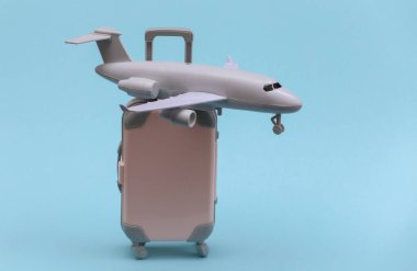 Hava yolculuğu konsepti. Mini plastik seyahat valizi ve mavi arka planda uçak..