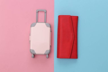 Seyahat konsepti. Mini plastik seyahat valizi ve çanta pembe mavi pastel arka planda. Asgari düzeyde. Üst manzara, düz uzanma
