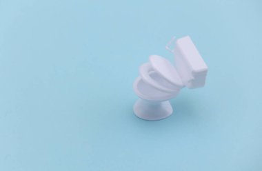 Mavi arka planda mini beyaz tuvalet. Minimalizm.