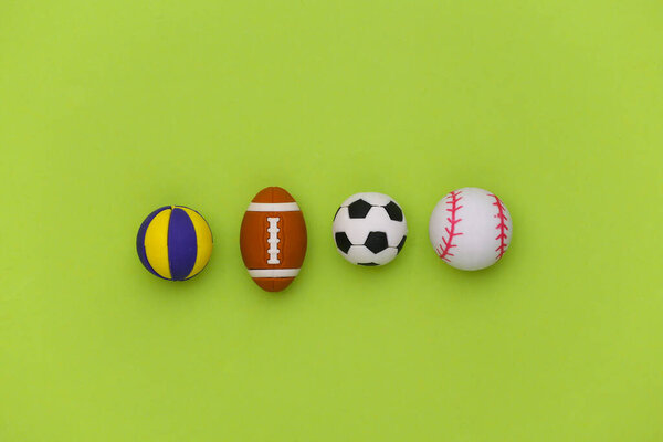 Мини мячи различных видов спорта на зеленом фоне. Концепция минимализма. Вид сверху. Плоский лежал.