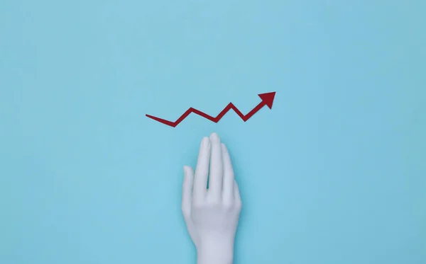 Mannequin\'s hand and red growth arrow tending upward on a blue background.