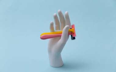 Beyaz manken elinde mavi arka planda jilet var. Güzellik, kişisel bakım konsepti