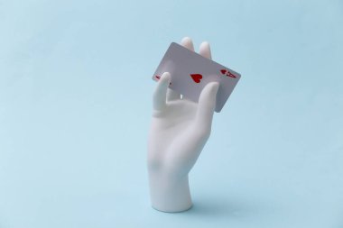 Kupa ası olan beyaz manken el mavi arka planda duruyor. Poker, kart oyunu