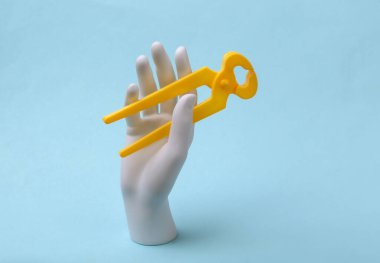 Beyaz manken el, mavi arka planda forseps tutuyor. Yenileme konsepti, endüstri. Minimalizm