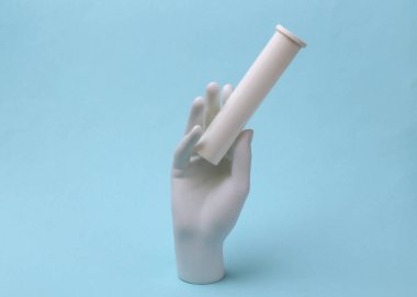 Mavi arka planda beyaz manken elinde ilaç şişesi var.