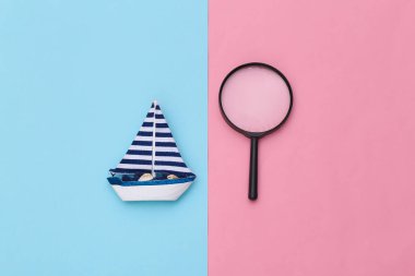 Mavi pembe arka planda yelkenli ve büyüteç. Minimalizm seyahat konsepti. Üst Manzara. Düz yatıyordu