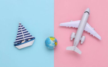 Yelkenli ve hava uçağı, mavi pembe arka planda bir dünya. Seyahat minimalizmi konsepti. Üst Manzara. Düz yatıyordu