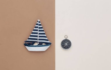 Kahverengi bej arka planda yelkenli ve pusula. Seyahat konsepti. Üst görünüm