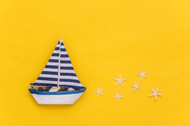 Sarı arka planda denizyıldızı olan yelkenli. Seyahat minimalizmi konsepti. Üst Manzara. Düz yatıyordu