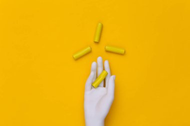 Beyaz manken elinde sarı arka planda AA tipi piller var. Üst görünüm