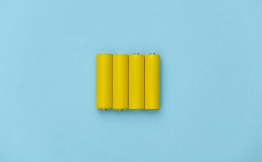 Mavi pastel arka planda dört sarı AA batarya. Üst görünüm