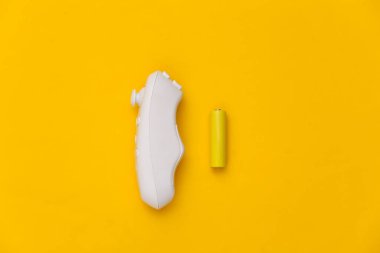 Kablosuz joystick ve sarı arka planda iki pil. Üst görünüm