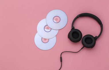 Pembe arka planda CD 'leri olan Stereo kulaklıklar. Üst görünüm