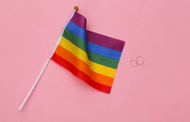 LGBT düğünü. LGBT gökkuşağı bayrağı ve pembe arka planda altın halkalar. Hoşgörü, özgürlük