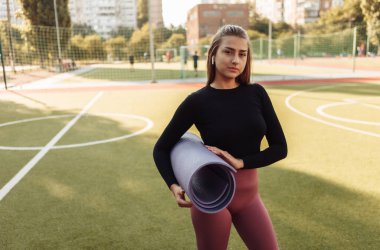 Açık havada paspas tutan formda bir kadın. Açık hava egzersizi.