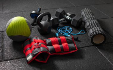 İşlevsel spor ekipmanları. Kettlebell ve atlama halatı, dambıllar, ilaç topu, masaj rulosu, siyah zeminde ağırlıklar. Vücut geliştirme ve fitness