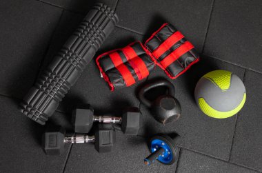 İşlevsel spor ekipmanları. Kettlebell ve atlama halatı, dambıllar, ilaç topu, masaj rulosu, siyah zeminde ağırlıklar. Vücut geliştirme ve fitness