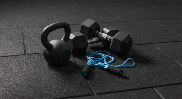 Functional training Sports equipment. Kettlebell and skipping rope, dumbbells on a dark black floor. Bodybuilding and fitness