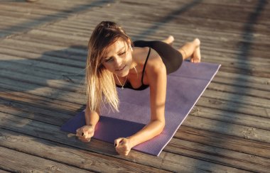 Formda genç atletik bir kadın sabahları dışarıda karın kasları üzerinde çalışıyor.