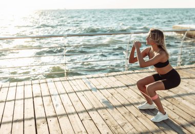 Güzel, formda bir kadın plajda spor yapıyor..