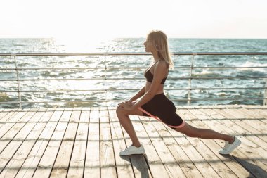 Güzel, formda bir kadın plajda spor yapıyor..