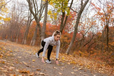 Genç zinde kadın koşucu hazırlan sonbahar parkında ya da ormanda koş.