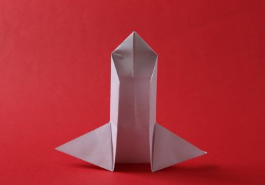 Origami uzay mekiği kırmızı arka planda. Minimalizm. Açılış.