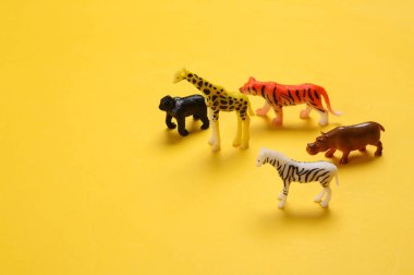 Sarı arka planda oyuncak vahşi hayvanlar. Hayvanları kurtar.