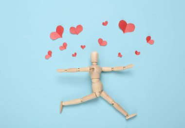 Mutlu ahşap kukla ve kağıt kesiği kırmızı kalpler mavi arka planda. Sevgililer Günü konsepti